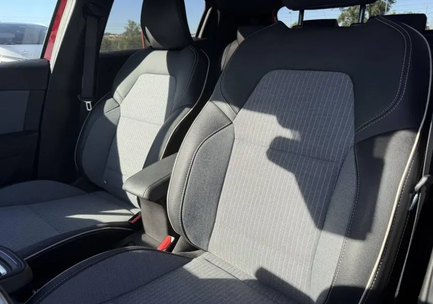 Vue intérieure des sièges avant gris clair et foncé de la Renault Clio 1.0 Eco-G 100ch Techno 2025, avec accoudoir central.