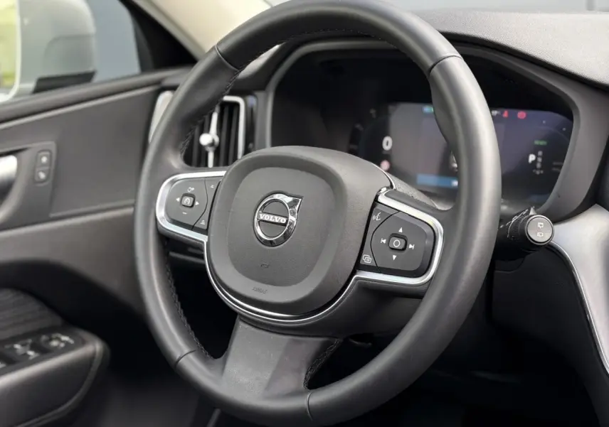 Volant simili-cuir noir de Volvo XC60 T6 AWD PHEV 2024 vu de face avec commandes intégrées et tableau de bord digital.