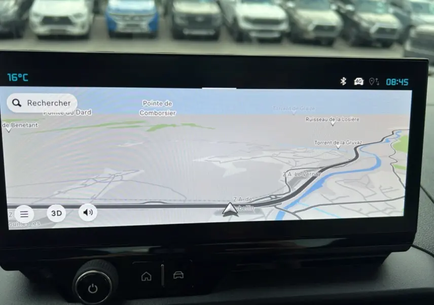 Écran tactile du système de navigation du Citroën Berlingo 2025, avec vue sur parking flou en arrière-plan.