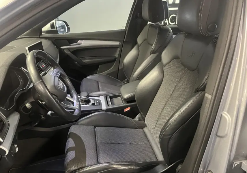 Vue intérieure côté conducteur de l'Audi Q5 S line 2019, sièges sport en cuir noir avec volant multifonction.