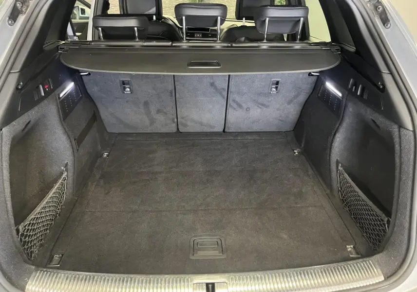 Coffre spacieux de l'Audi Q5 gris 2019 vu de l'arrière avec banquette rabattable et filets latéraux.