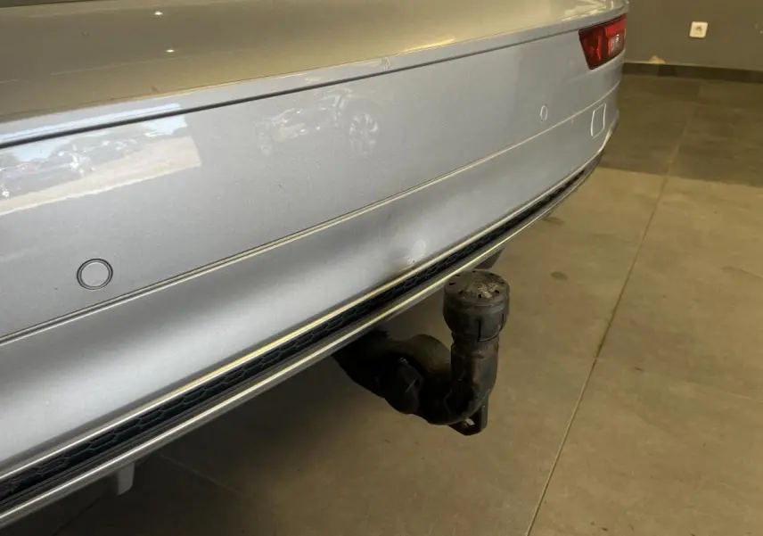 Gros plan sur le pare-chocs arrière gris métallisé de l'Audi Q5 avec crochet d'attelage électrique visible.