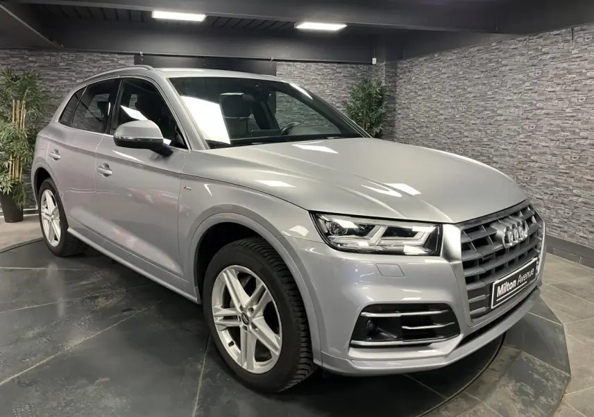 Audi Q5 gris métallisé vue 3/4 avant droit en intérieur avec jantes alliage et calandre distinctive