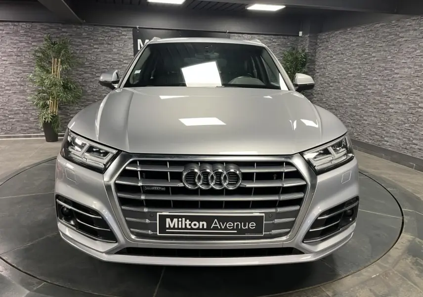 Vue frontale d'un Audi Q5 gris métallisé avec calandre S line et phares à LED dans un showroom.