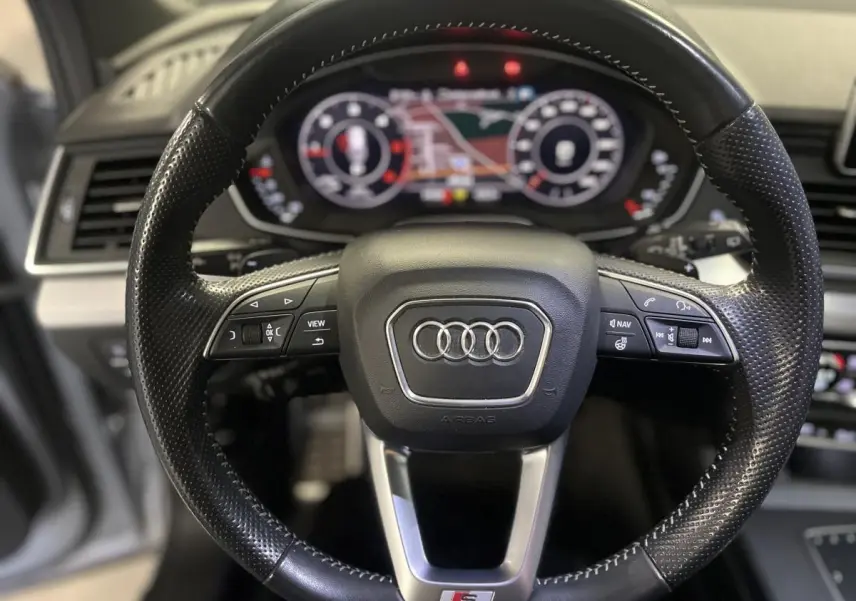 Volant cuir perforé noir S line avec commandes multifonctions et tableau de bord numérique flou en arrière-plan