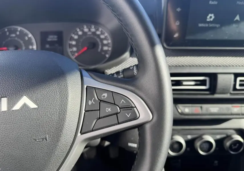 Gros plan sur le volant côté droit du Dacia Jogger gris schiste, avec commandes multifonctions et tableau de bord partiel.