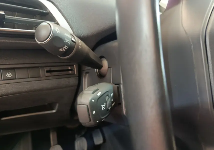 Gros plan sur la manette de commande des feux et régulateur de vitesse côté gauche du volant cuir du Peugeot 3008 bleu 2022.
