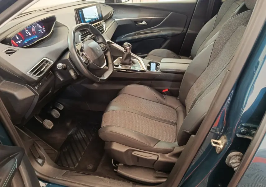 Intérieur avant gauche du Peugeot 3008 bleu 2022, volant cuir, tableau de bord numérique et console centrale moderne.