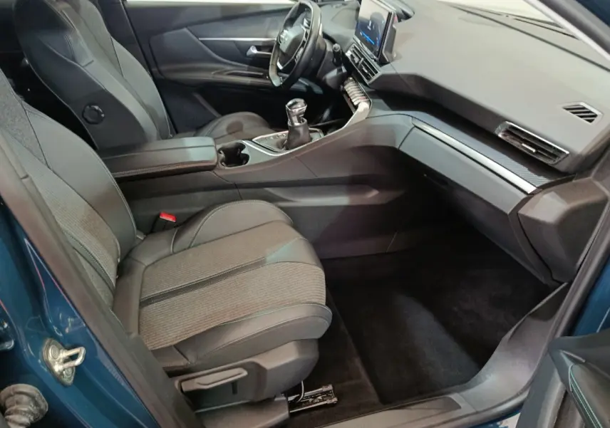 Intérieur avant droit du Peugeot 3008 bleu 2022, sièges tissu et cuir, tableau de bord moderne avec écran tactile central.