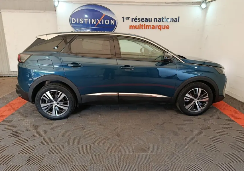 Profil côté droit d'un Peugeot 3008 bleu 2022 garé en intérieur sur sol damier noir et rouge.