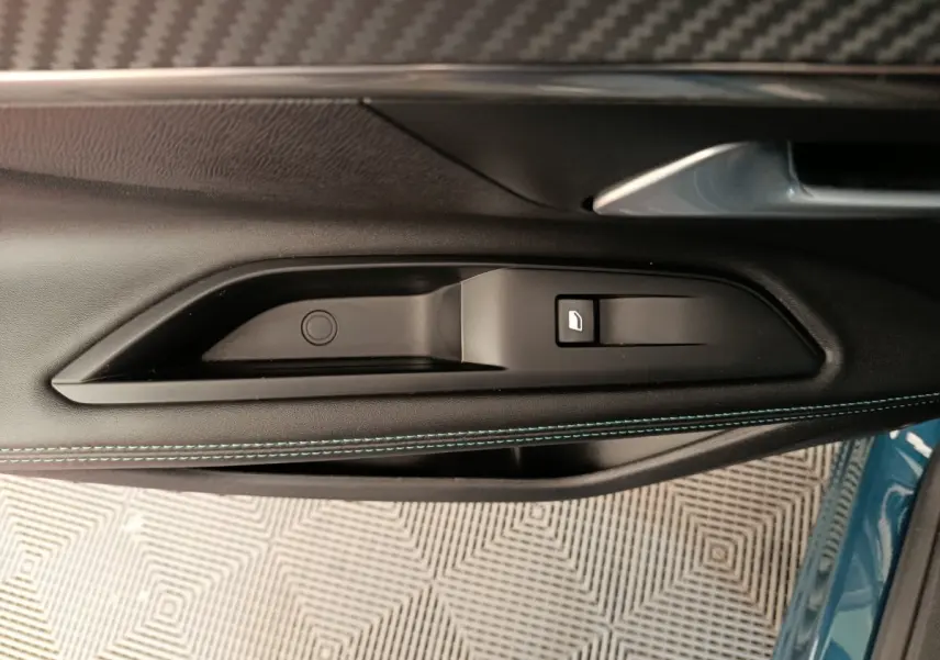 Gros plan sur la poignée intérieure côté gauche de la porte d’un Peugeot 3008 bleu avec surpiqûres bleues.