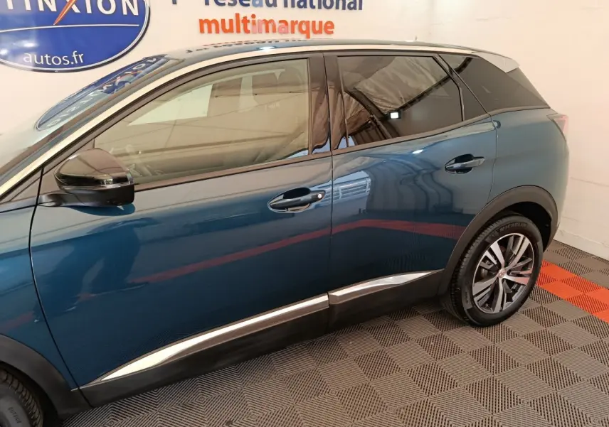 Vue latérale côté gauche du Peugeot 3008 bleu avec jantes alliage et toit noir en intérieur showroom.