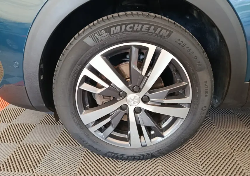 Gros plan sur la roue avant gauche du Peugeot 3008 bleu, mettant en valeur la jante alliage et le pneu Michelin.