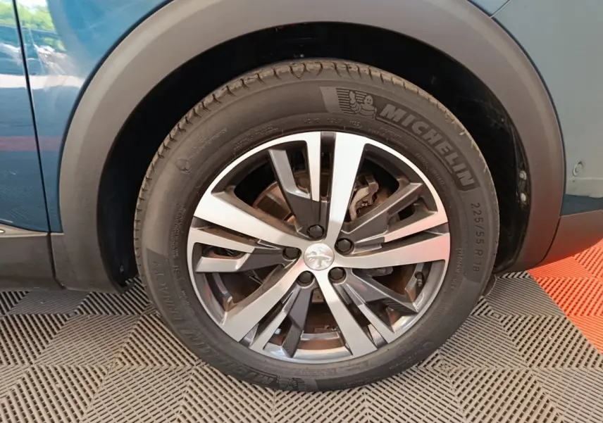 Gros plan sur la roue avant gauche bleu du Peugeot 3008 avec jante alliage et pneu Michelin visible.