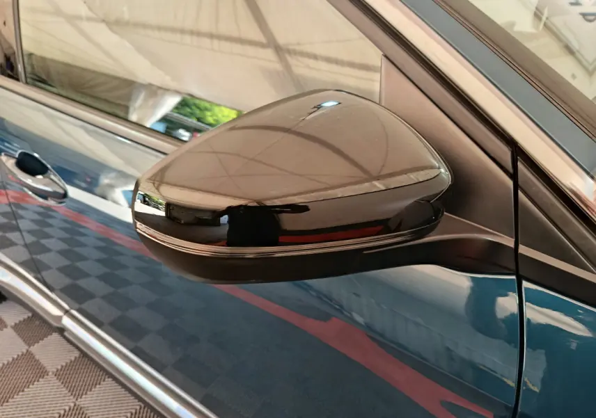 Gros plan sur le rétroviseur droit noir brillant du Peugeot 3008 bleu, avec reflet du plafond intérieur.