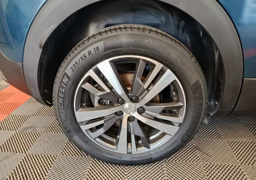 Gros plan sur la roue avant gauche d'une Peugeot 3008 bleu, jante alliage 18 pouces avec pneu Michelin.