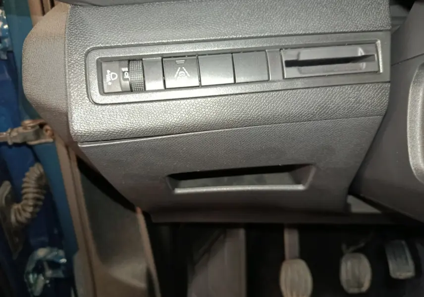 Gros plan sur les commandes de réglage des phares et aides à la conduite côté gauche d'un Peugeot 3008 bleu 2022.