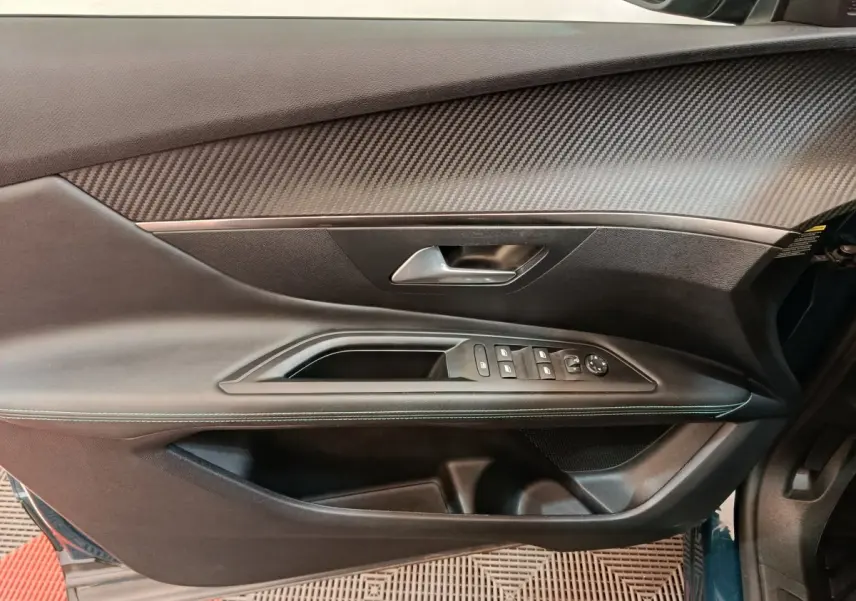 Gros plan sur la porte côté gauche du Peugeot 3008 bleu, montrant les commandes électriques et le revêtement noir texturé.