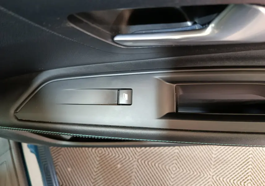 Gros plan sur la commande de lève-vitre côté conducteur dans l'intérieur noir du Peugeot 3008 PureTech 130 S&S Allure 2022.