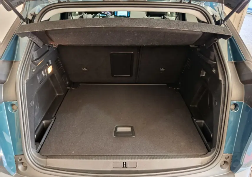 Coffre ouvert vu de l'arrière d'un Peugeot 3008 bleu 2022, montrant un espace de chargement spacieux et propre.