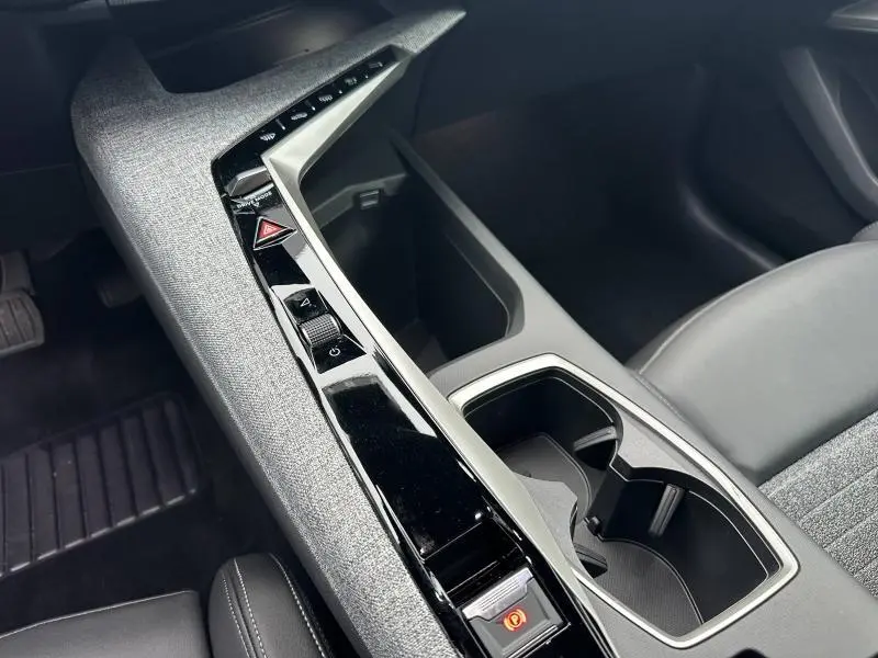 Détail de la console centrale noire et grise avec commandes et porte-gobelets du Peugeot 3008 Hybrid 2025 vue côté passager.