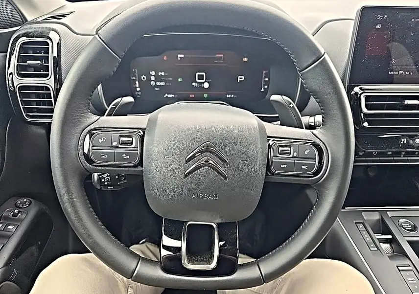 Vue intérieure centrée sur le volant cuir noir du Citroën C5 Aircross 2025 avec tableau de bord digital et écran tactile.