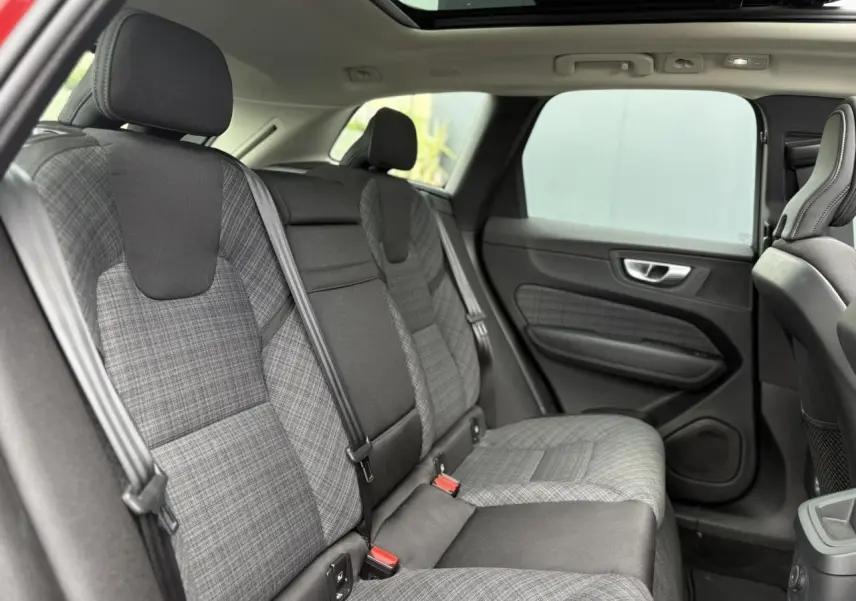Vue latérale droite de l'intérieur arrière du Volvo XC60 2024, sièges en tissu gris à motif carreaux et ceintures noires.