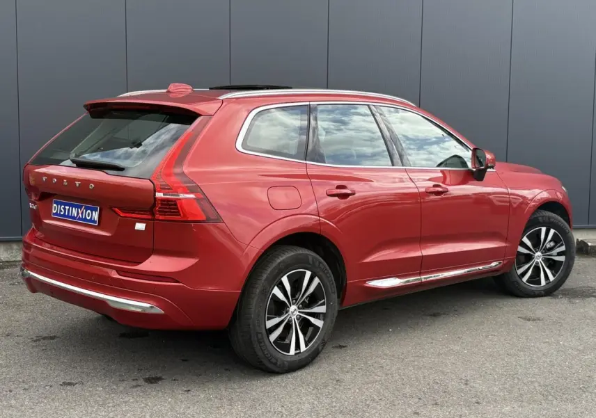 Vue 3/4 arrière droite d'un Volvo XC60 rouge Fusion avec jantes alliage et contours chromés des vitres