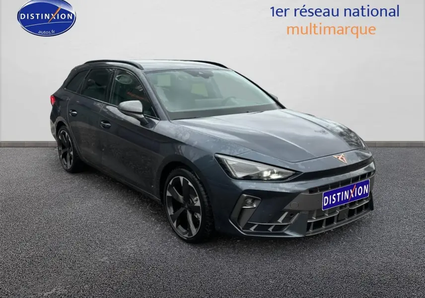 Vue 3/4 avant gauche d'une CUPRA Leon ST gris magnétique avec jantes alu et barres de toit visibles.