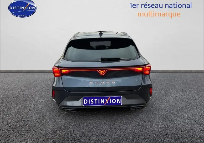 Vue arrière d'une CUPRA Leon ST gris magnétique avec feux arrière LED allumés et double sortie d'échappement.