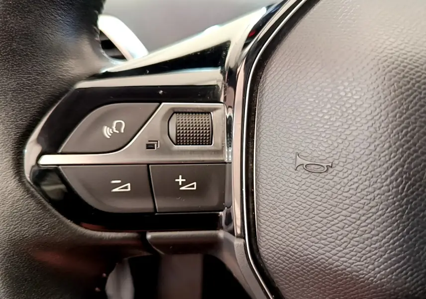 Gros plan sur les commandes gauche du volant cuir noir du Peugeot 3008 gris foncé, version Puretech 130 S&S ACTIVE.