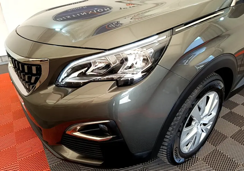 Vue 3/4 avant droit d'un Peugeot 3008 gris foncé mettant en valeur son phare LED et sa calandre distinctive.