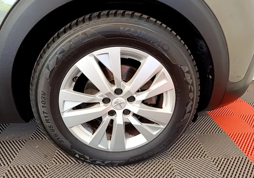 Gros plan sur la roue avant gauche du Peugeot 3008 gris foncé, mettant en valeur la jante alliage et le pneu Kumho.