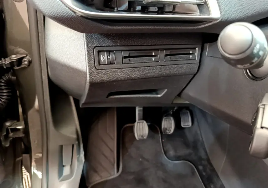 Vue rapprochée côté gauche du poste de conduite du Peugeot 3008 gris foncé, avec pédales et commandes visibles.