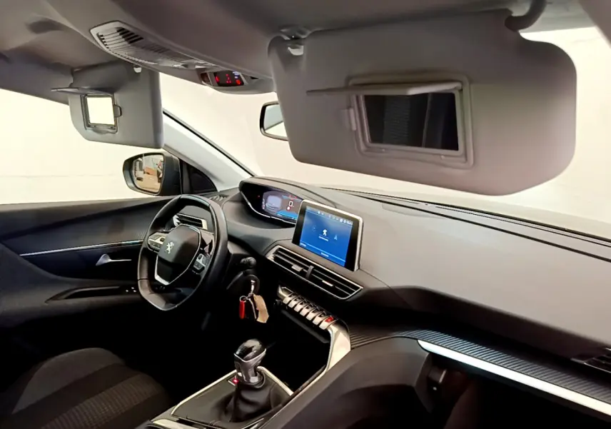 Intérieur de Peugeot 3008 gris foncé, vue côté conducteur, tableau de bord avec écran tactile et volant cuir multifonctions.