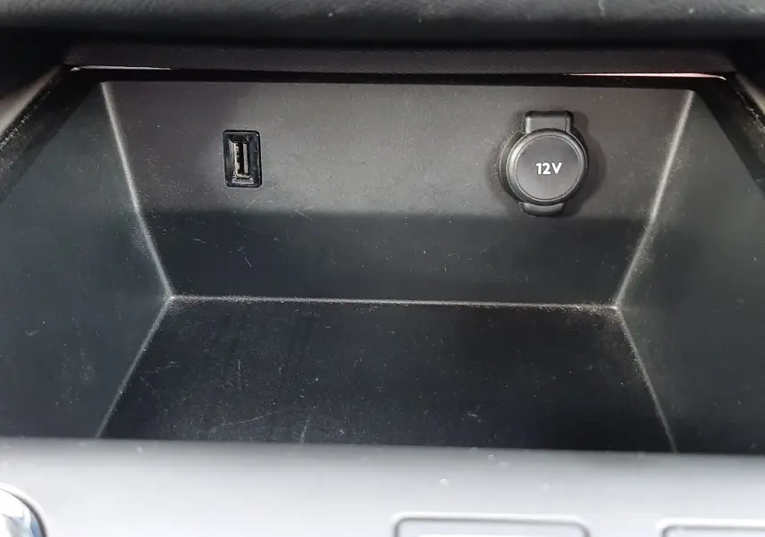Gros plan sur la prise USB et la prise 12V dans le compartiment de rangement intérieur du Citroën C5 Aircross blanc.
