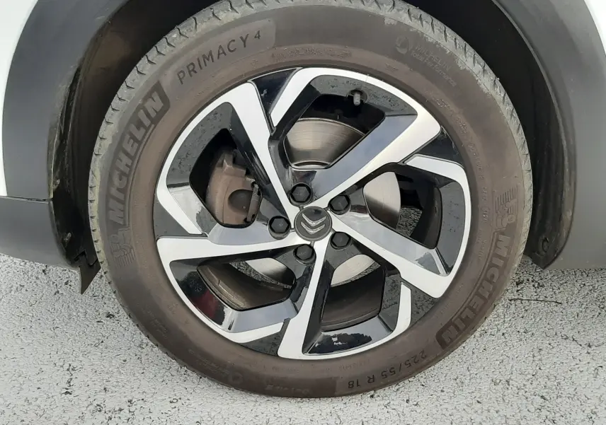 Gros plan sur la roue avant droite d'un Citroën C5 Aircross blanc avec jante alliage bicolore et pneu Michelin.