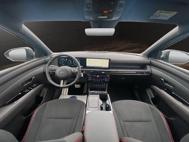 Vue intérieure avant du Hyundai Tucson 1.6 Hybrid gris foncé, tableau de bord moderne avec écran tactile central et volant multifonctions.