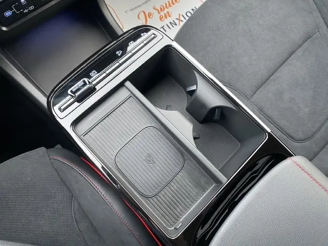 Gros plan sur la console centrale noire du Hyundai Tucson 1.6 Hybrid 239 N Line Creative avec porte-gobelets et commandes tactiles.