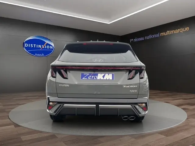 Vue arrière d’un Hyundai Tucson gris foncé hybride 2026 avec hayon motorisé et feux LED distinctifs en intérieur showroom.
