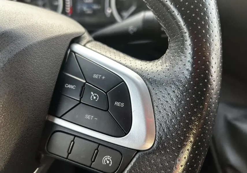 Gros plan sur les commandes de régulateur de vitesse au volant en cuir noir perforé de l'Iveco Daily blanc 2020.