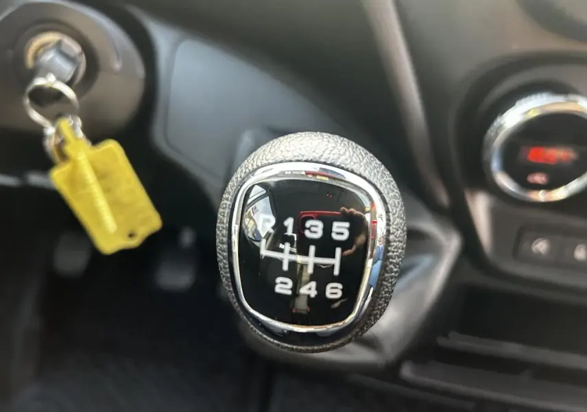 Gros plan sur le levier de vitesses manuel du Iveco Daily blanc 2020, avec clé insérée et tableau de bord en arrière-plan.