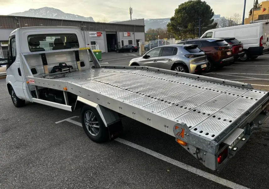 IVECO Daily blanc vu en 3/4 arrière côté gauche avec plateau métallique perforé et cabine simple.