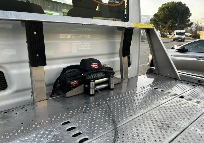 Gros plan sur le treuil Warn fixé à la benne arrière du plateau d’un Iveco Daily blanc, vue latérale droite.