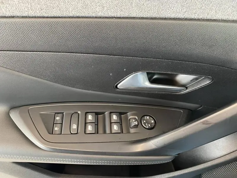 Détail de la porte côté conducteur d'une Peugeot 308 gris Artense 2022, avec commandes électriques des vitres et rétroviseurs.