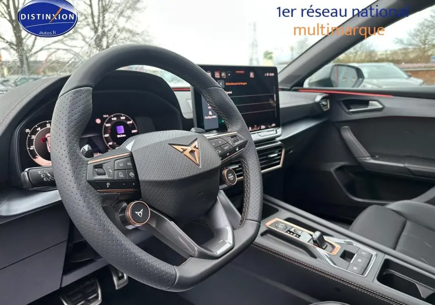 Intérieur de la CUPRA LEON ST 2025, vue côté conducteur sur volant sport et écran tactile central.