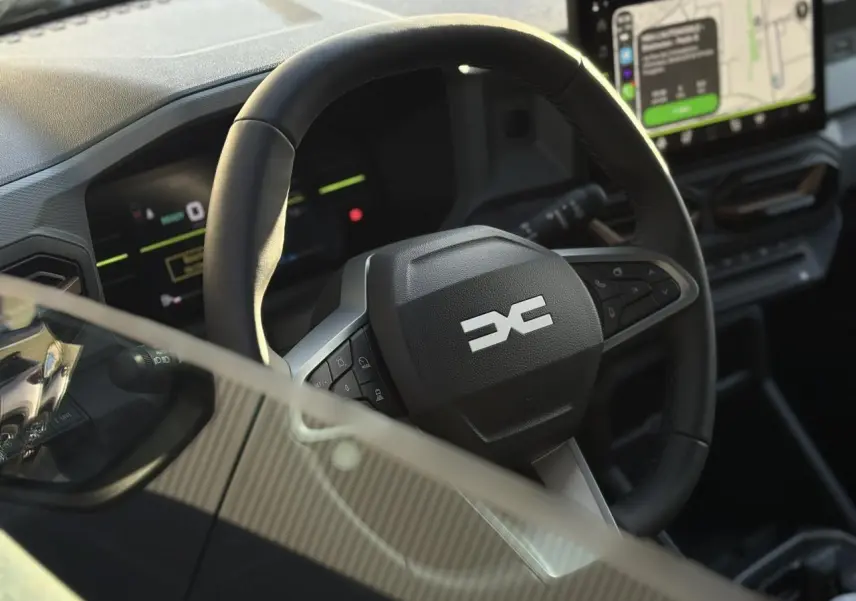 Vue rapprochée du volant noir du Dacia Duster 2026 avec tableau de bord digital et écran tactile GPS.