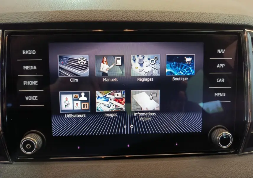 Écran tactile central du tableau de bord du Skoda Karoq blanc, affichant le menu multimédia et réglages.