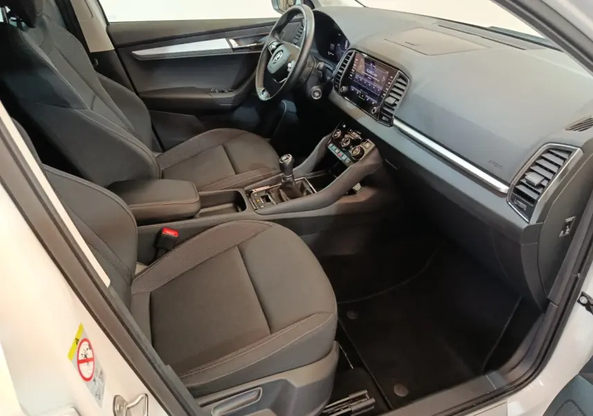 Intérieur avant droit du Skoda Karoq blanc 2024, sièges noirs, tableau de bord avec écran tactile et volant multifonctions cuir.