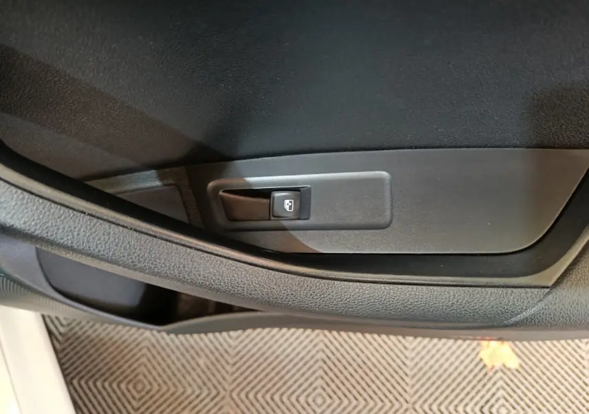 Bouton de commande de lève-vitre sur la porte intérieure côté conducteur d'un Skoda Karoq blanc 2024.